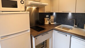 A compact kitchen with a microwave, toaster, coffee maker, and dishwasher. - Charming Apartment Near Slopes with Balcony, Parking, and Modern Amenities (Les Gets)