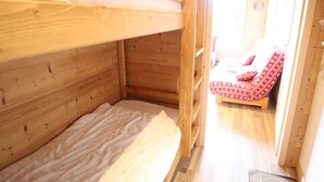 A wooden cabin room with bunk beds and a small bed. - Charming Apartment Near Slopes with Balcony, Parking, and Modern Amenities (Les Gets)