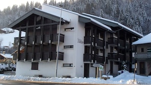 A multi-story building with balconies, a sign indicating 'Residence', and a sign pointing to 'Tannenges Geneva'. - Central Apartment in Les Gets, Steps from Village and Slopes (Les Gets)