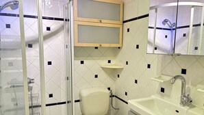 A bathroom with a glass-enclosed shower, a toilet, a sink, and a mirror above the sink. - Central Apartment in Les Gets, Steps from Village and Slopes (Les Gets)