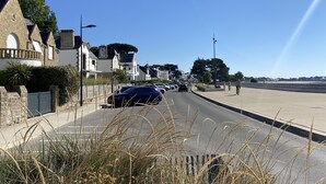 Una calle residencial con casas, coches aparcados y un camino peatonal.
