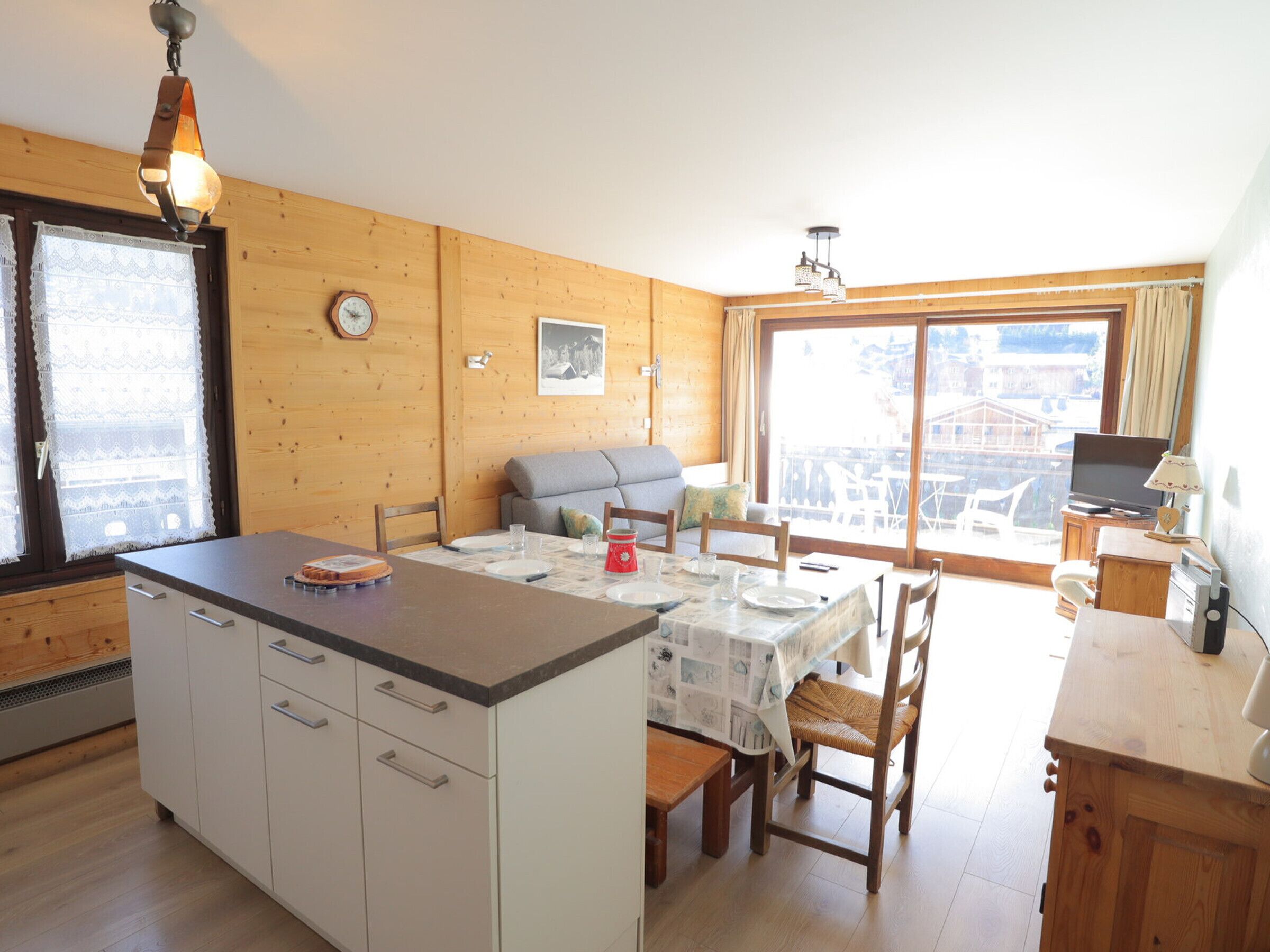 Een gezellig chalet met een eethoek, keuken en een groot raam met uitzicht op de bergen.