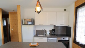 Eine kleine Küche mit Mikrowelle, Kaffeemaschine und Geschirrspüler.