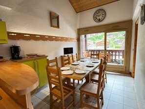 A dining area with wooden furniture, a clock on the wall, and a view of the outside.