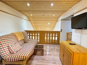 A cozy room with a checkered sofa, a small table, and a television mounted on the wall.