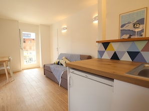 A compact living space with a kitchenette, a sofa, a dining table, and a view of the outside.