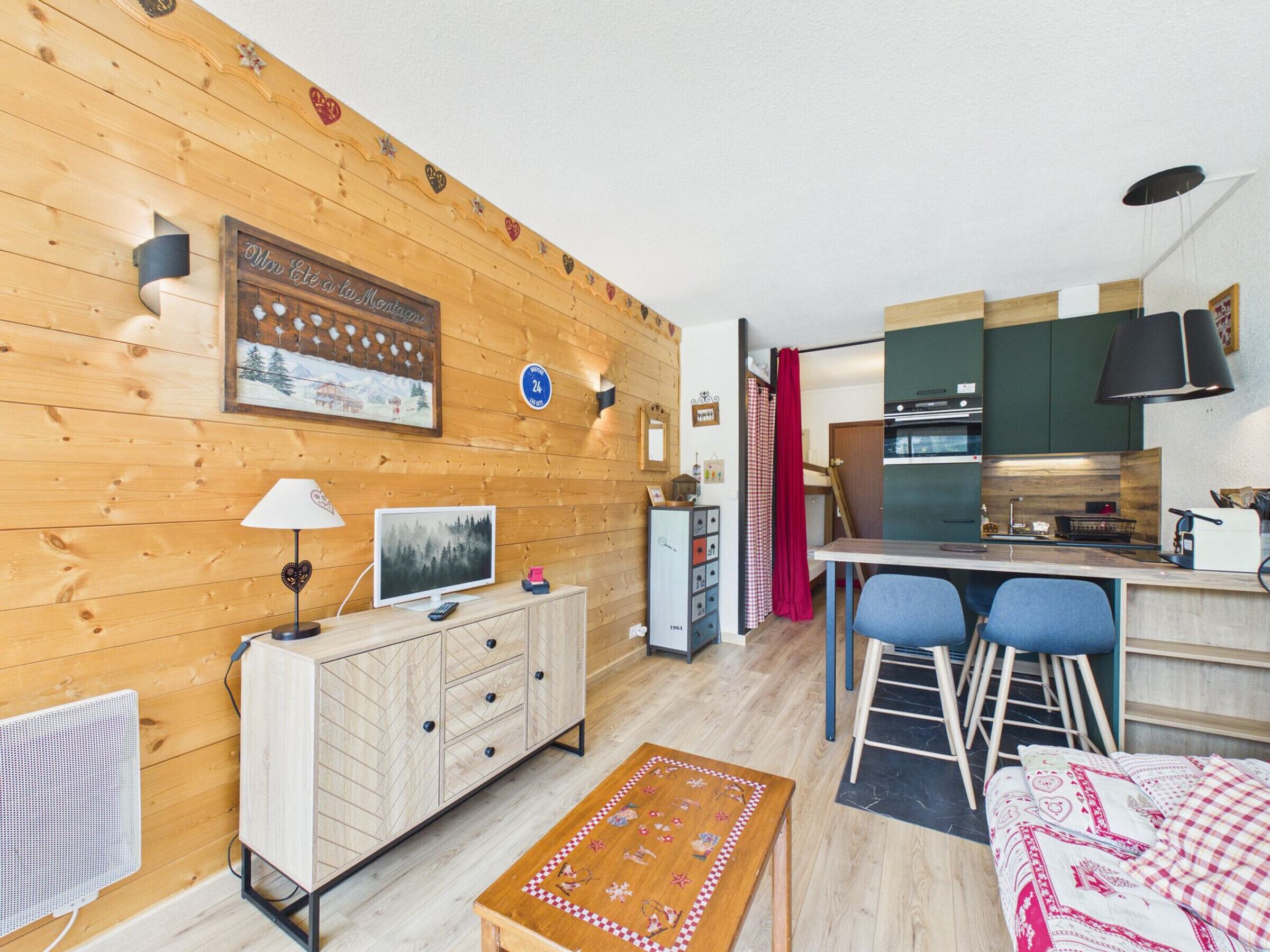 A cozy wooden interior with a dining area, kitchen, and a TV on a wooden cabinet.