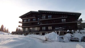 A multi-story hotel with a modern architectural design, featuring balconies and a snow-covered landscape. - Ski-In/Ski-Out Studio with Pool, Tennis & Mountain Views - 1km from Les Gets Center (Les Gets)