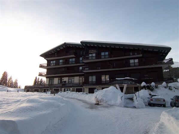 A multi-story hotel with a modern architectural design, featuring balconies and a snow-covered landscape.