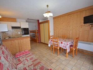 Um espaço compacto para viver, com cozinha compacta, área de refeições e sofá.