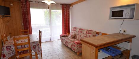 A compact kitchen with a dining table, chairs, a sofa, and a microwave.