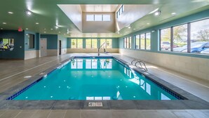 Una piscina interior con agua cristalina, rodeada de paredes con grandes ventanales.