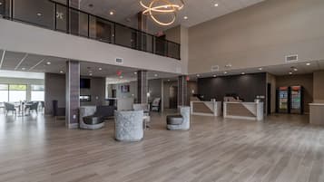 A spacious lobby with a high ceiling, a reception desk, seating areas, and a vending machine.