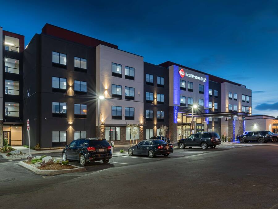 A modern hotel with multiple floors, a parking lot, and illuminated signage.