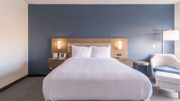 A hotel room with a large bed, two bedside tables with lamps, a chair, and a small round table.