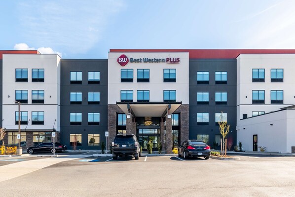 Un hotel Best Western PLUS de varios pisos con una fachada moderna, múltiples espacios de estacionamiento y una entrada despejada.