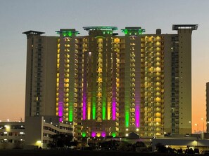 A high-rise building with multiple balconies and illuminated windows.