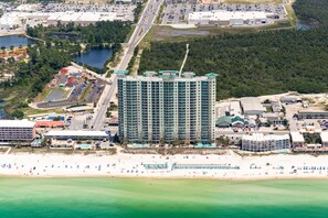 Un hotel moderno de muchas plantas, con aparcamiento y zona de playa con sombrillas.