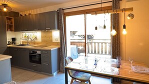 Eine moderne Küche mit Essbereich, inklusive großem Fenster, einem Tisch für vier Personen und einem eingebauten Backofen.