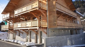 Ein mehrstöckiges Holzchalet mit Balkonen, einem Steinfundament und einer Bergkulisse.