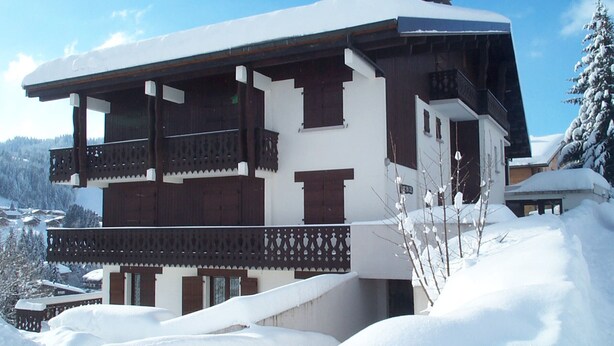 A multi-story chalet with a balcony, surrounded by snow-covered landscape and trees. - Studio with terrace and garage in Les Gets (Les Gets)
