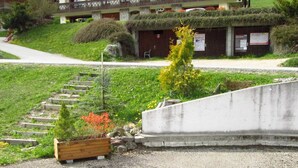 A hotel with a garden area featuring a staircase, a wooden planter, and a concrete retaining wall. - Studio with terrace and garage in Les Gets (Les Gets)