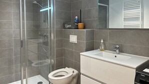 A modern bathroom with a glass-enclosed shower, a toilet, and a vanity with a mirror. - Modern Stylish Studio with Spa Access, Central Location, Close to Slopes (Les Gets)