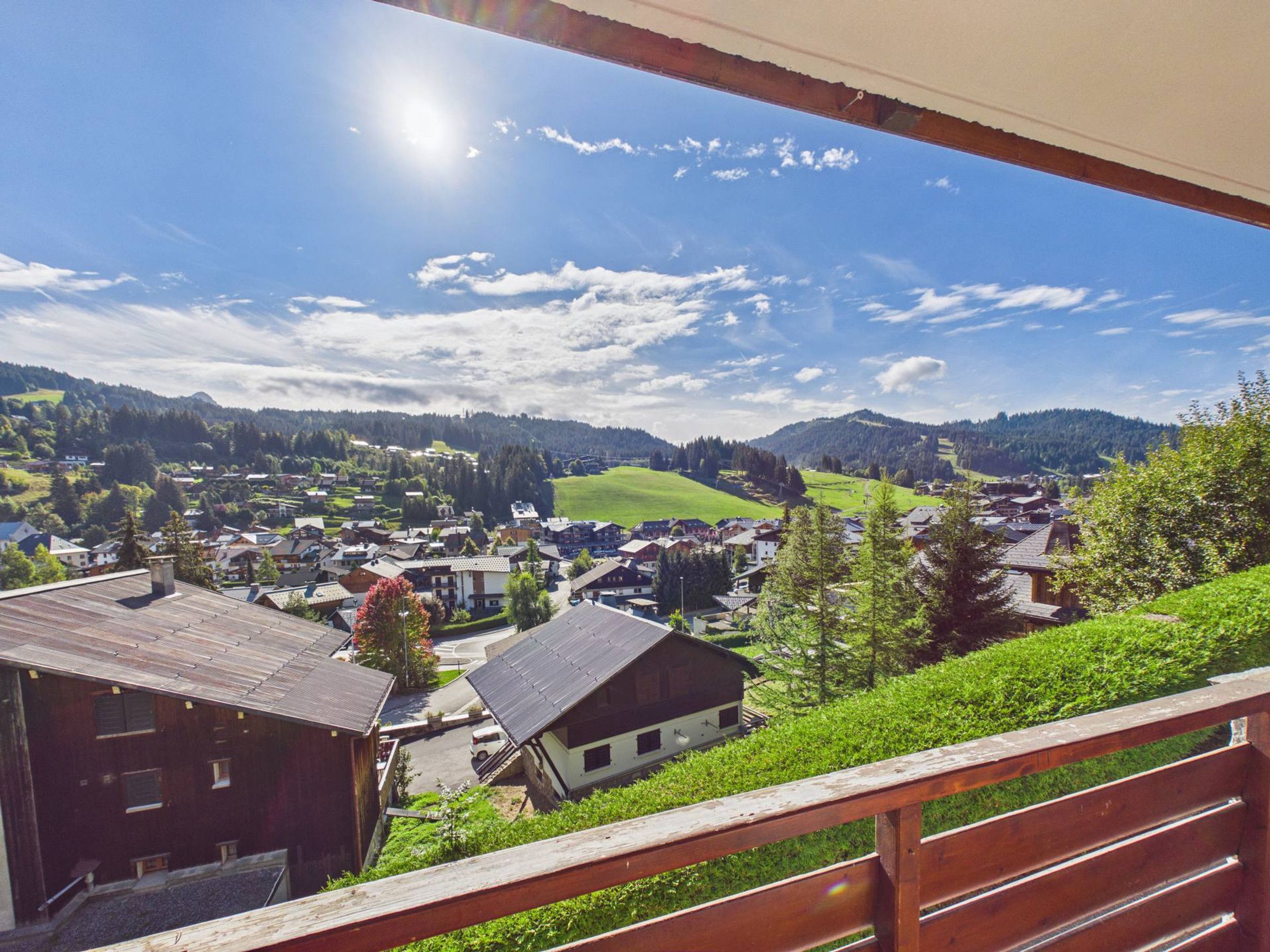 Vista desde un balcón sobre un pueblo con casas, cielo despejado y un paisaje montañoso.