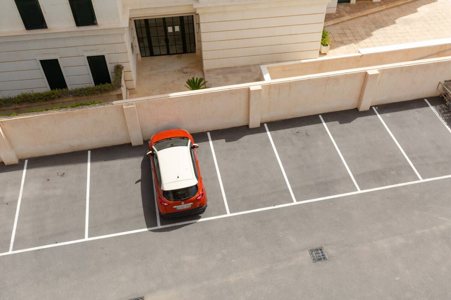 An aerial view of a parking lot with a single car parked in a designated space.