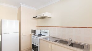 Uma cozinha compacta com geladeira, micro-ondas, fogão e pia dupla.