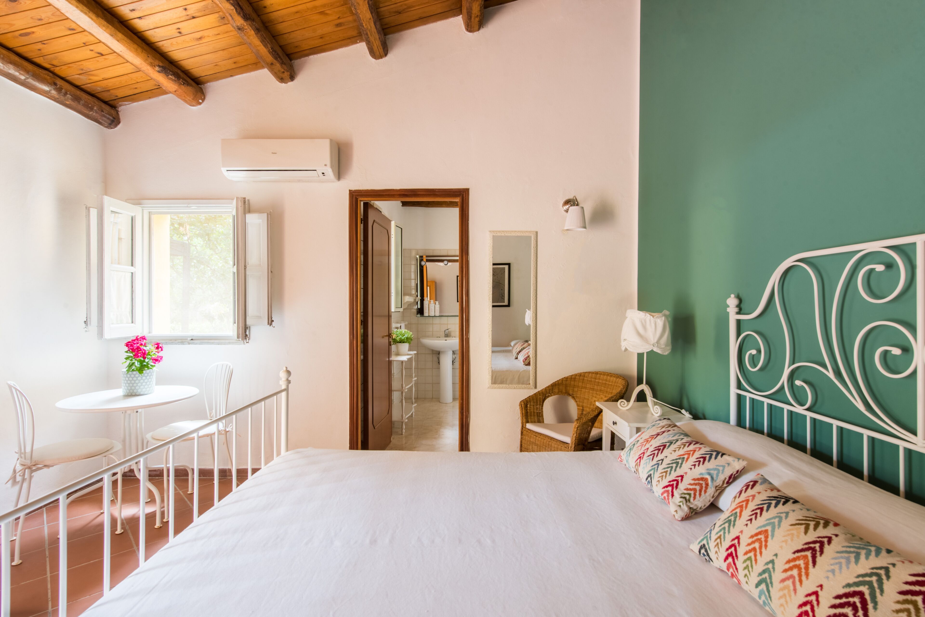 Une chambre à coucher avec un lit, une fenêtre, une petite table avec des chaises et une vue sur la salle de bain.