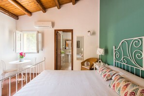 Un dormitorio con cama, ventana, una pequeña mesa con sillas y vistas al baño.