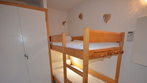A bunk bed with a wooden frame, a white door, and a white wall with a heart-shaped decoration. - Ski-In/Ski-Out Apartment in Les Gets - 3 Stars, Balcony, Mountain Views, Free Shuttle (Les Gets)