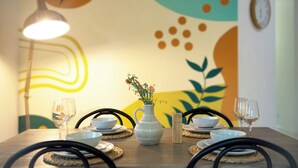 Una mesa de comedor con un jarrón de flores, dos copas de vino y fuentes sobre individuales.
