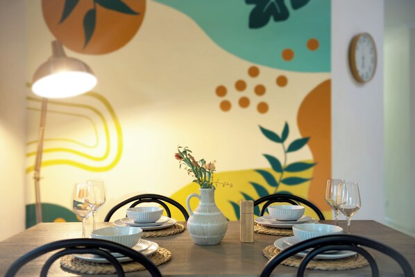 Uma mesa de jantar com um vaso de flores, duas taças de vinho e tigelas sobre jogos americanos.