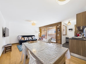 A compact living space with a sofa, dining table, and kitchenette.