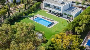 Une maison moderne dotée d’une piscine, entourée d’une végétation luxuriante et d’une pelouse bien entretenue.