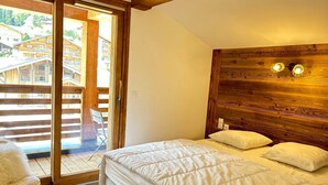 Ein Schlafzimmer mit Holzkopfbrett, einem Bett mit weißer Bettwäsche und einer Glastür zum Außenbereich.