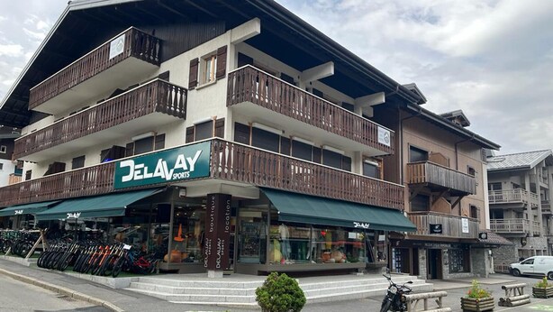 A multi-story building with a DELAY SPORTS store on the ground floor, featuring balconies and a bike parking area.