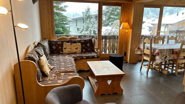 A cozy wooden interior with a sofa, a small table, and a chair.