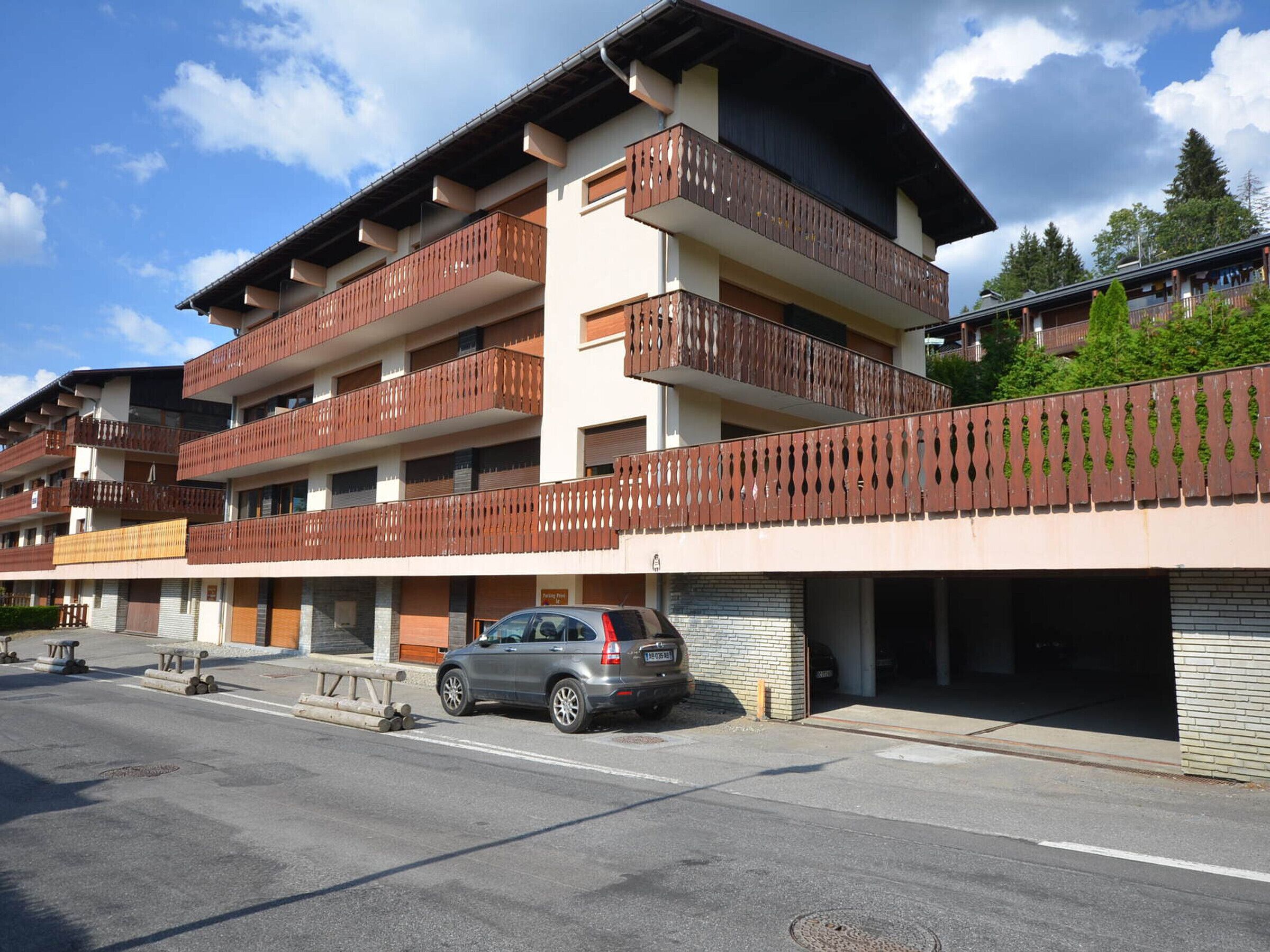 A multi-story hotel with balconies, a parking area, and a building entrance.