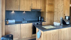A modern kitchen with wooden cabinets, a granite countertop, stainless steel appliances, and a small island with a coffee maker.