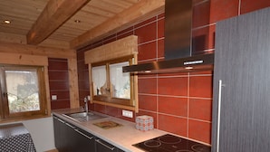 Una cocina moderna con armarios oscuros, una campana extractora de acero inoxidable y un ventanal con vistas al exterior.