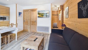 Ein gemütliches Wohnzimmer mit einer Couch, einem Holzesstisch mit Stühlen, einem kleinen Couchtisch und einem Fernseher.