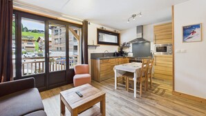 Eine moderne Wohnung mit Küche, Essbereich und einem Balkon mit Blick auf einen Skigebiet.