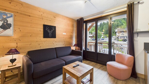 Ein gemütliches Wohnzimmer mit Holzwand, einer Couch, einem Couchtisch und einem Sessel.