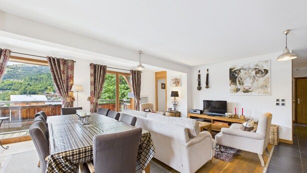 Un salón amplio con comedor, ventanas grandes y televisor.