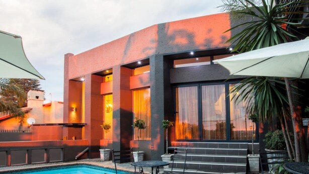 Un edificio moderno con piscina, mobiliario exterior y amplias ventanas.