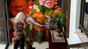 Una escalera con un mural floral vibrante, una araña y una pequeña mesa con alfombra.