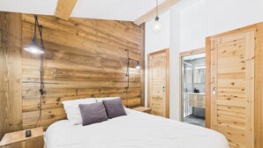 A bedroom with a wooden headboard, a bed with white bedding, two bedside lamps, and a wooden wardrobe. - Les Gets - Lovely apartment with balcony and fireplace near the slopes (Les Gets)